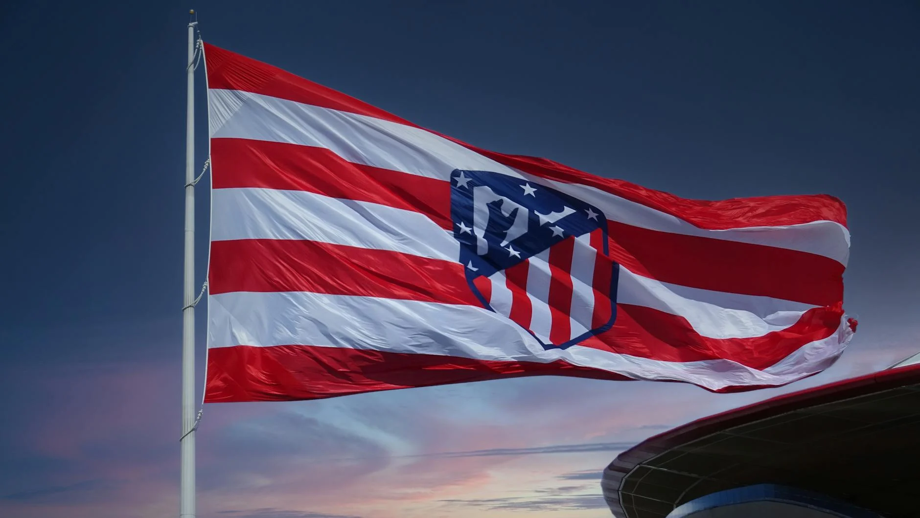 Waving Atlético Madrid flag against a sunset sky, symbolizing team spirit in Madrid.