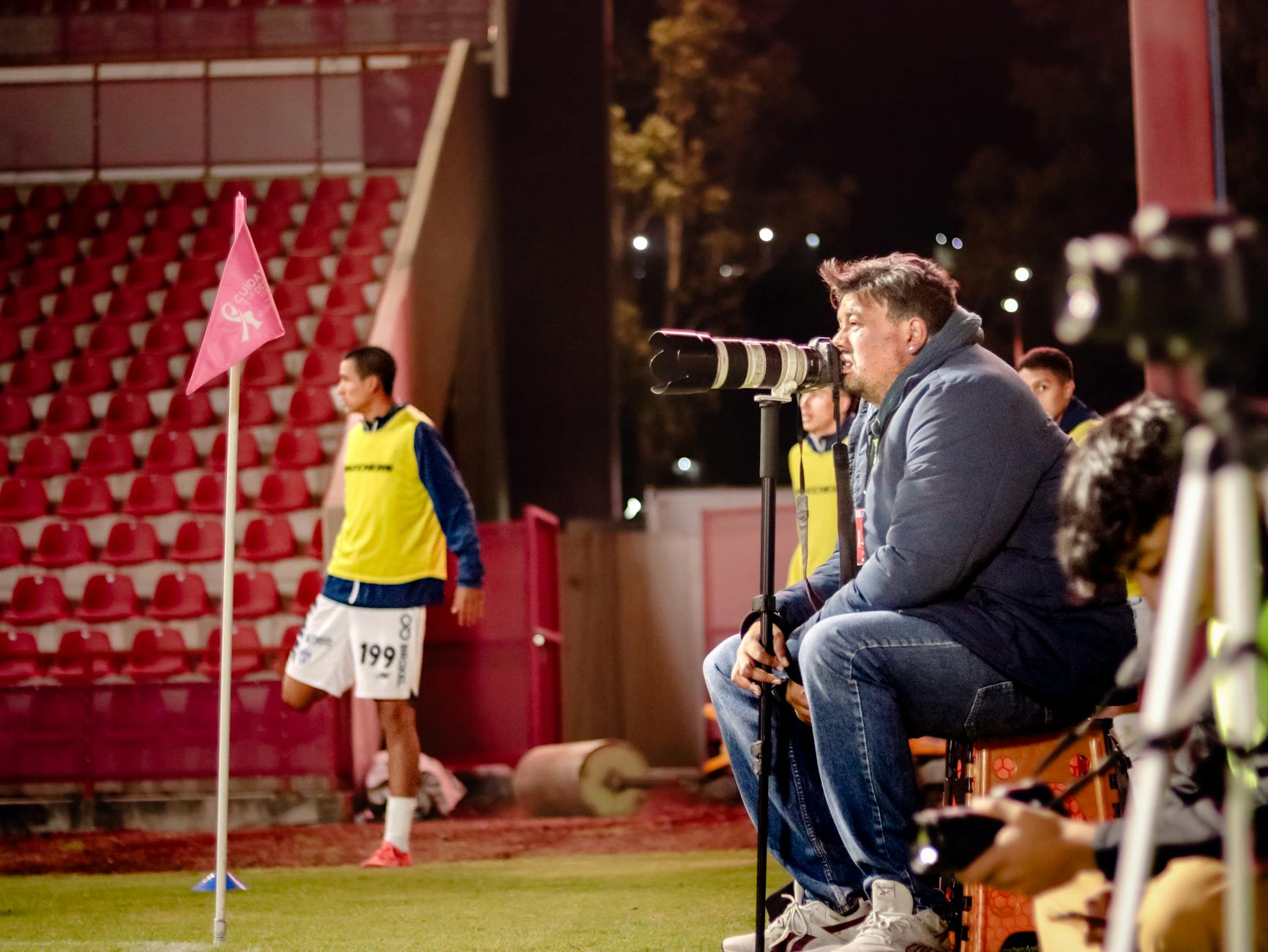 Soccer coach intensely watches game at night stadium, focused on strategy.