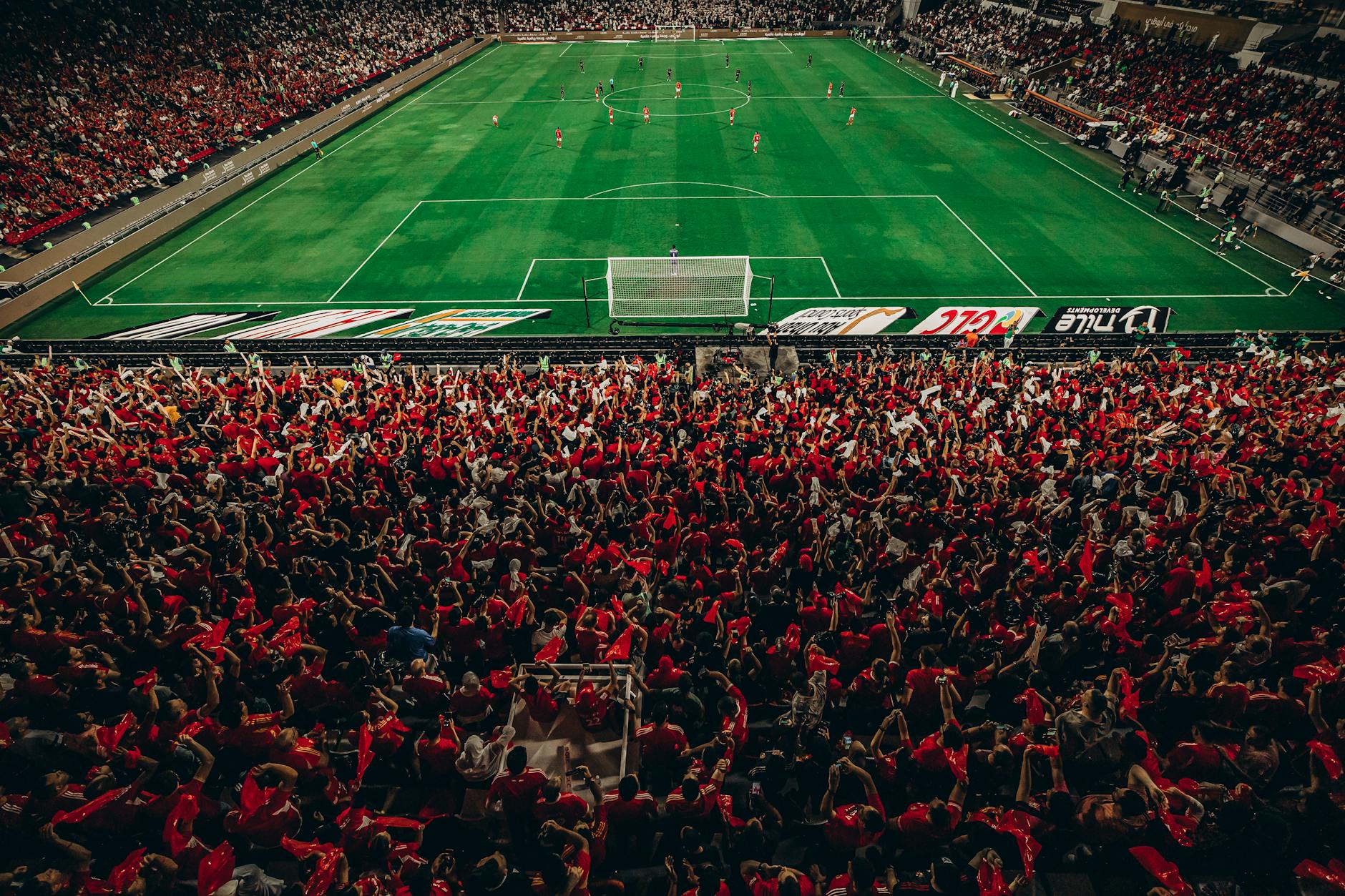 Aerial shot of a lively football match with enthusiastic fans in a packed stadium.