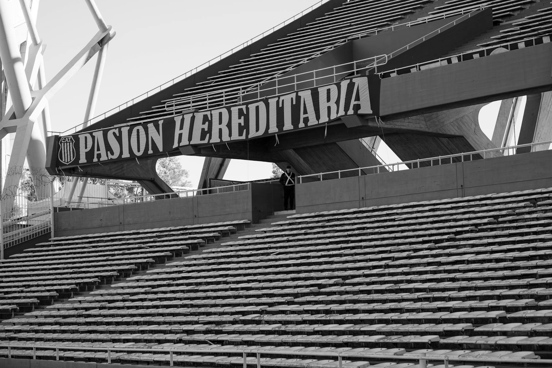 Black and white photo of empty grandstands at a Córdoba stadium, highlighting the structure and atmosphere.
