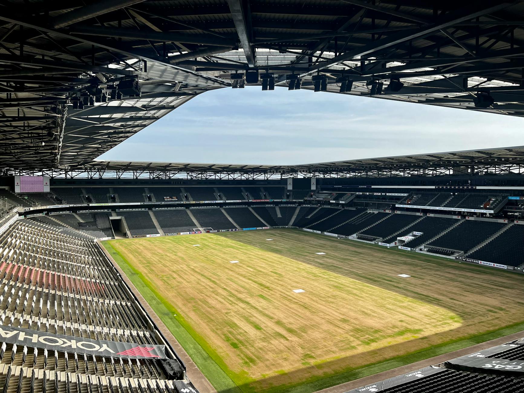 Wide-angle view of an empty football stadium in Milton Keynes, showcasing the field and seating areas.