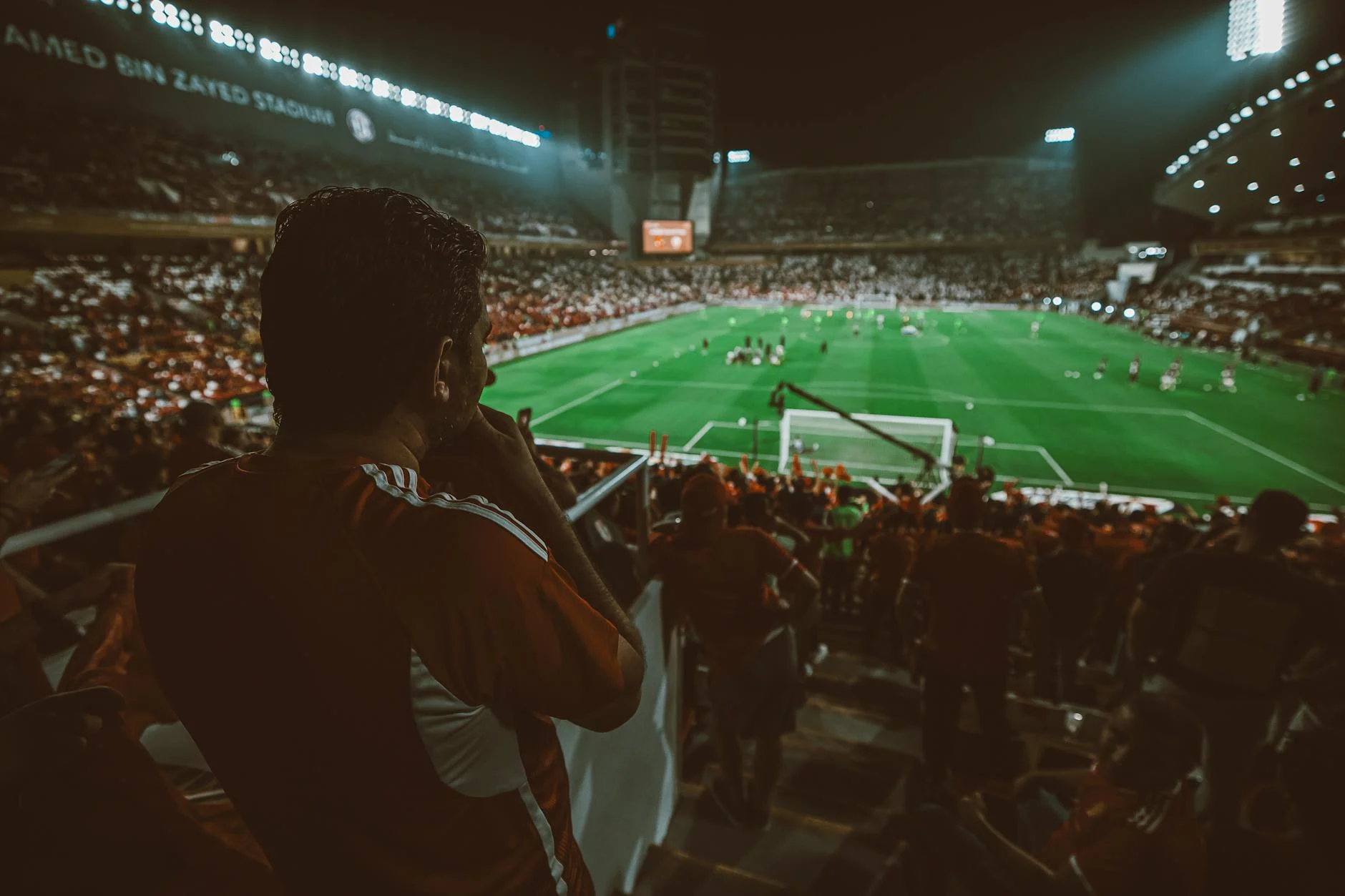 Fans cheering during a thrilling night football match at Mohamed Bin Zayed Stadium, Abu Dhabi.